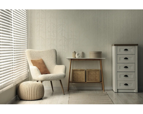 Lichte woonkamer met gestructureerd behang met bamboepatroon, witte teddy fauteuil, gebreide poef, houten consoletafel en witte ladekast.