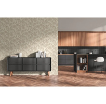 Licht vliesbehang met bladmotief in een modern ingerichte kamer met zwart dressoir en aangrenzende keuken met visgraatparket.