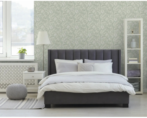 Moderne slaapkamer met donkergrijs gestoffeerd bed, wit beddengoed en licht behang met bladmotief op de muur.