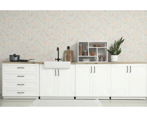 Lichte keuken met witte kasten, keramische spoelbak, zwarte kraan en bloemetjesbehang in landelijke stijl.