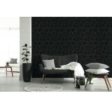 Donker behang met een licht, geometrisch cirkelpatroon in een modern ingerichte woonkamer met een grijze bank en kamerplanten.