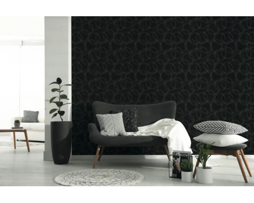 Donker behang met een licht, geometrisch cirkelpatroon in een modern ingerichte woonkamer met een grijze bank en kamerplanten.