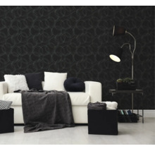 Moderne woonkamer met donker vliesbehang met cirkelpatroon, een witte bank met kussens en een zwarte vloerlamp.