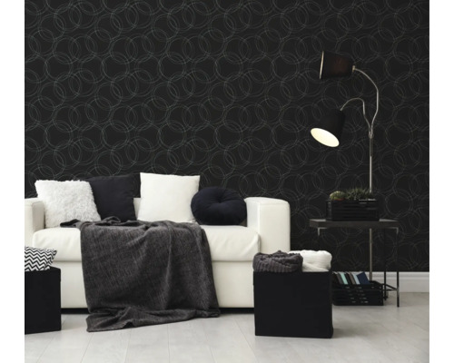 Moderne woonkamer met donker vliesbehang met cirkelpatroon, een witte bank met kussens en een zwarte vloerlamp.