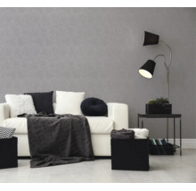 Vliesbehang met cirkelpatroon in woonkamer met witte bank, zwarte vloerlamp en sierkussens. Moderne sfeer in grijs en wit.
