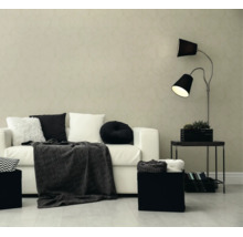 Moderne woonkamer met behang met cirkelpatroon, witte bank, zwart-witte kussens, een donkere deken en een vloerlamp met twee lampenkappen.