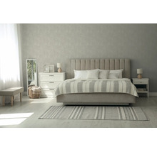 Slaapkamer met gestoffeerd bed, verticaal gecapitonneerd hoofdbord, gestreepte sprei, nachtkastjes, spiegel en behang met patroon.