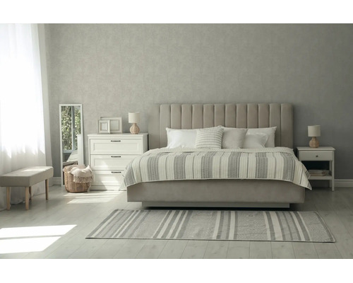 Slaapkamer met gestoffeerd bed, verticaal gecapitonneerd hoofdbord, gestreepte sprei, nachtkastjes, spiegel en behang met patroon.
