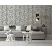 Vliesbehang met takkenpatroon in een moderne woonkamer met grijze bank en witte bijzettafel.