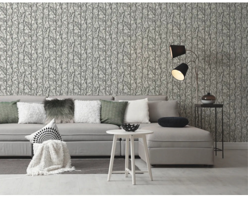 Vliesbehang met takkenpatroon in een moderne woonkamer met grijze bank en witte bijzettafel.