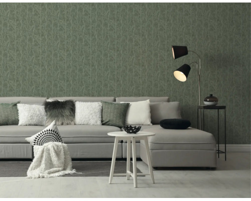 Moderne woonkamer met grijze bank, witte bijzettafel en behang met subtiel takkenpatroon.