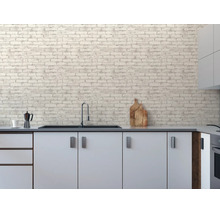 Moderne keuken met witte kasten en vliesbehang in baksteenlook op de muur. Inclusief spoelbak, kraan en keukenaccessoires.