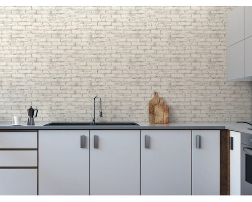 Moderne keuken met witte kasten en vliesbehang in baksteenlook op de muur. Inclusief spoelbak, kraan en keukenaccessoires.