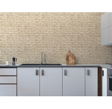 Keuken met behang in baksteenlook als achterwand boven witte kasten en een zwarte gootsteen met chromen kraan.