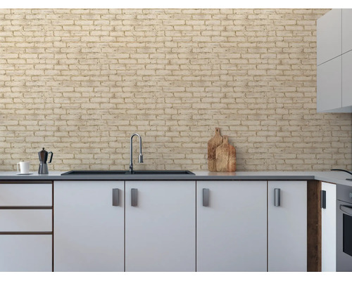 Keuken met behang in baksteenlook als achterwand boven witte kasten en een zwarte gootsteen met chromen kraan.