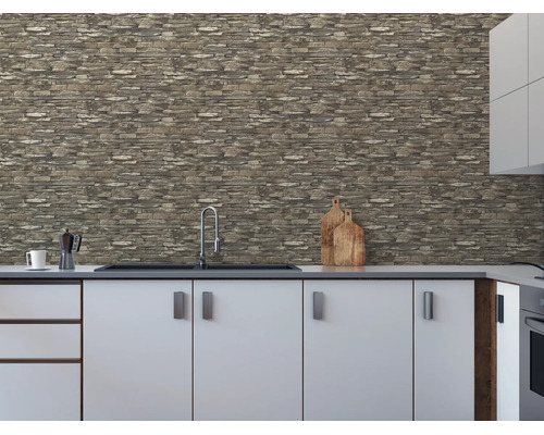 Vliesbehang met steenlook op een keukenmuur boven een wit keukenblok met spoelbak.