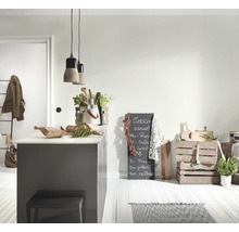 Lichte, moderne keuken met grijs kookeiland, twee betonnen hanglampen, houten kisten voor opslag en een beschreven krijtbord.