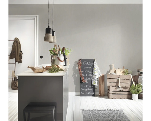 Lichte, georganiseerde keuken met lichtgrijze muur, kookeiland, houten kisten, kruiden en moderne hanglampen van beton en metaal.