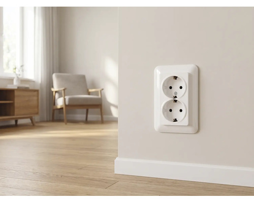 Dubbele wandcontactdoos met randaarde op een lichte muur in een moderne woonkamer met houten vloer en fauteuil.