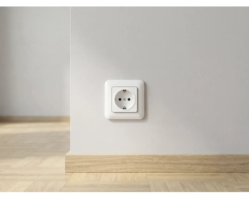 Stopcontact op een witte muur boven een lichte houten plint in een lichte kamer.