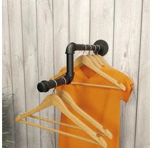 Wandgarderobe in industrieel design van zwarte metalen buizen met houten kledinghangers voor een lichte houten wand.
