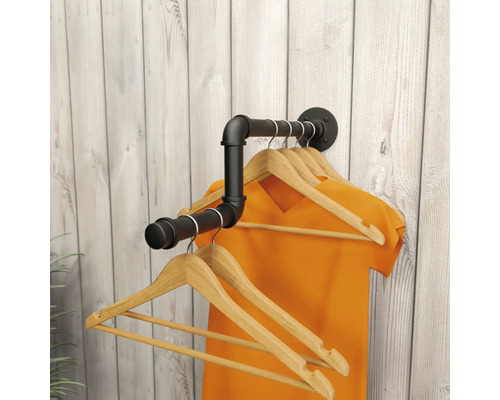 Wandgarderobe in industrieel design van zwarte metalen buizen met houten kledinghangers voor een lichte houten wand.