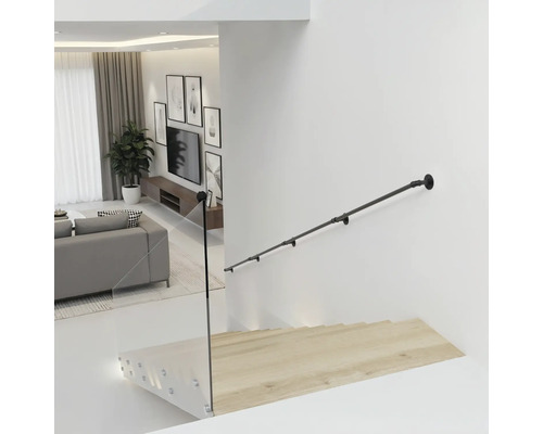 Zwarte metalen trapleuning in industriële stijl aan een witte muur boven een houten trap met glazen balustrade in een moderne woonkamer.