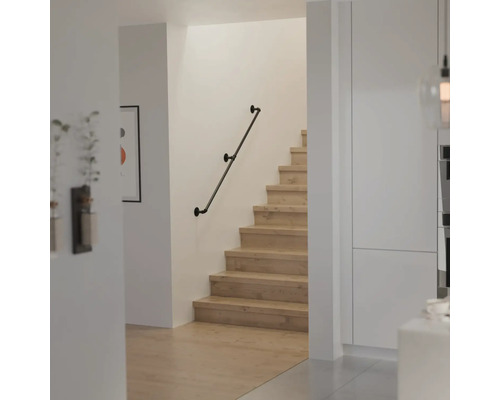 Moderne trap met houten treden en een wandleuning in industrieel design van metalen buizen.
