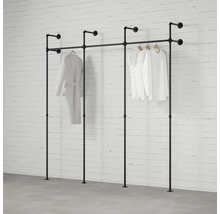 Industrieel kledingreksysteem van zwarte metalen buizen, wand- en vloermontage, driedelig, met hangende kleding voor een bakstenen muur.