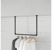 Aan het plafond gemonteerde kledingroede van metalen buizen in industrieel design met kledinghangers voor een bakstenen muur.