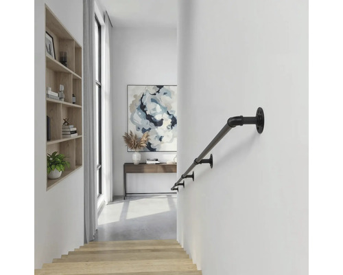 Zwarte metalen trapleuning in industriële stijl aan een witte wand in een lichte, moderne gang met houten trap.