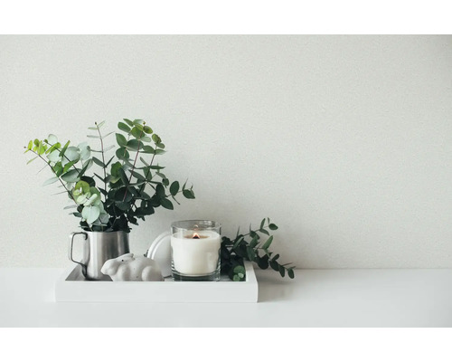 Heldere, georganiseerde opstelling op een wit dienblad met eucalyptus takken in een metalen kan, een brandende kaars en een keramieken konijn.