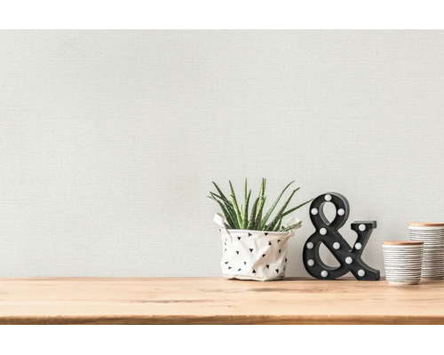 Structuurbehang op een wand achter een houten tafel met een plant en decoratieve items.