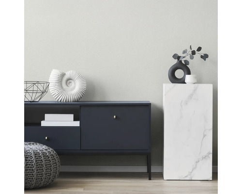 Moderne woonkamer met donker dressoir, marmerlook zuil, decoratieve schelp, vaas en grijze gebreide poef.