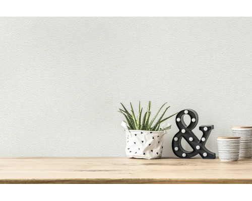Gestructureerd behang in een lichte kamer met een aloë vera, verlicht ampersand-teken en voorraadpotten op houten oppervlak.