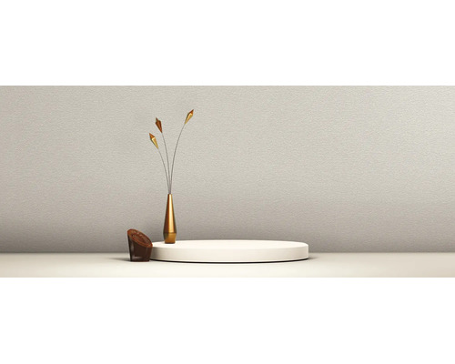 Getextureerde wand met een rond podium, een slanke gouden vaas met drie decoratieve takken en een kleine bruine gevlochten stoel.
