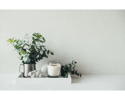 Heldere en georganiseerde decoratie op een wit dienblad met eucalyptustakken in een metalen kan, een kaars in glas en een konijnenbeeldje.