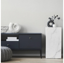 Moderne woonkamer met een donkerblauw dressoir, een grijze gebreide poef en een zuil met marmerlook tegen een lichte, gestructureerde wand.