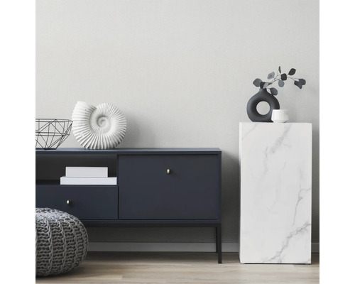 Moderne woonkamer met een donkerblauw dressoir, een grijze gebreide poef en een zuil met marmerlook tegen een lichte, gestructureerde wand.