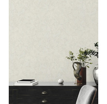 Gestructureerd behang met pleistereffect in een lichte kamer met donker dressoir, planten en decoratieve voorwerpen.