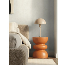 Paddenstoelvormige tafellamp op een moderne, sculpturale bijzettafel naast een bed met een getextureerd hoofdbord.