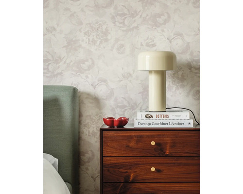 Lichte slaapkamer met gebloemd vliesbehang, een houten nachtkastje, een beige tafellamp en een groen hoofdbord.