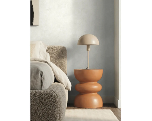 Moderne slaapkamer met gestructureerde muurverf, bouclé bed en paddenstoelvormige tafellamp op een sculpturale bijzetafel.