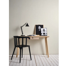 Minimalistische werkplek met een licht houten bureau met lade, een moderne zwarte stoel en een zwarte bureaulamp.