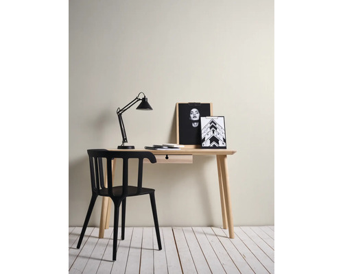 Minimalistische werkplek met een licht houten bureau met lade, een moderne zwarte stoel en een zwarte bureaulamp.