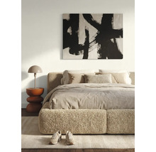 Moderne, lichte slaapkamer met een bed met bouclé-bekleding, een abstracte wanddecoratie, een sculpturale bijzettafel en een tafellamp.
