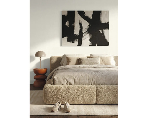 Moderne, lichte slaapkamer met een bed met bouclé-bekleding, een abstracte wanddecoratie, een sculpturale bijzettafel en een tafellamp.
