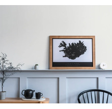 Ingelijste kaart van IJsland in houten lijst op een wandlijst boven een lichtblauwe lambrisering met decoratie.