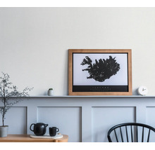 Wanddecoratie kaart IJsland in houten lijst op een wandplank in een minimalistische kamer met theepot en stoel.