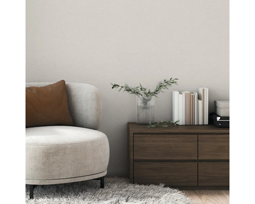 Moderne woonkamer met gestructureerde wandafwerking, een beige fauteuil met bruin kussen en een donkerhouten ladekast.